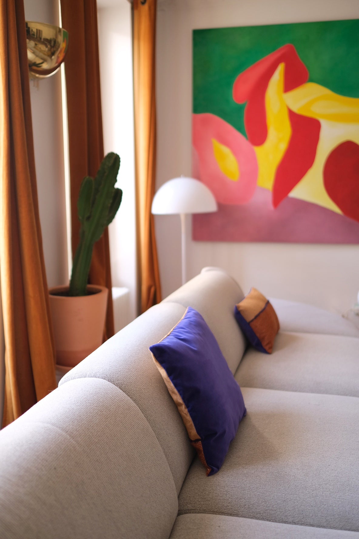 Coussin Horizon, 45x45cm. Les tons camel se marient merveilleusement au velours violet et lumineux de son verso. Les tissus viennent de la maison Elitis. Le coussin a été cousu à la main à Paris par l'un de nos artisans. Ici sur un canapé gris clair.