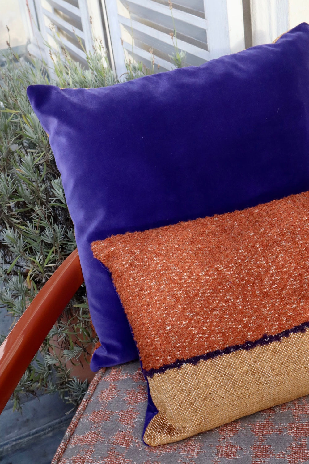 Coussin Horizon, 45x45cm. Les tons camel se marient merveilleusement au velours violet et lumineux de son verso. Les tissus viennent de la maison Elitis. Le coussin a été cousu à la main à Paris par l'un de nos artisans. Ici sur un fauteuil couleur terracotta.