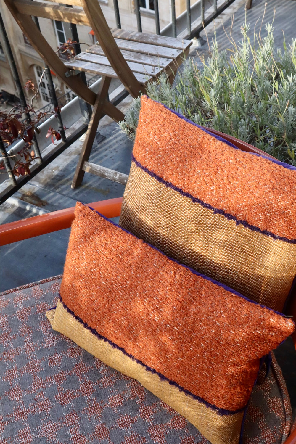Coussin Horizon, 45x45cm. Les tons camel se marient merveilleusement au velours violet et lumineux de son verso. Les tissus viennent de la maison Elitis. Le coussin a été cousu à la main à Paris par l'un de nos artisans. Ici sur un fauteuil couleur terracotta.