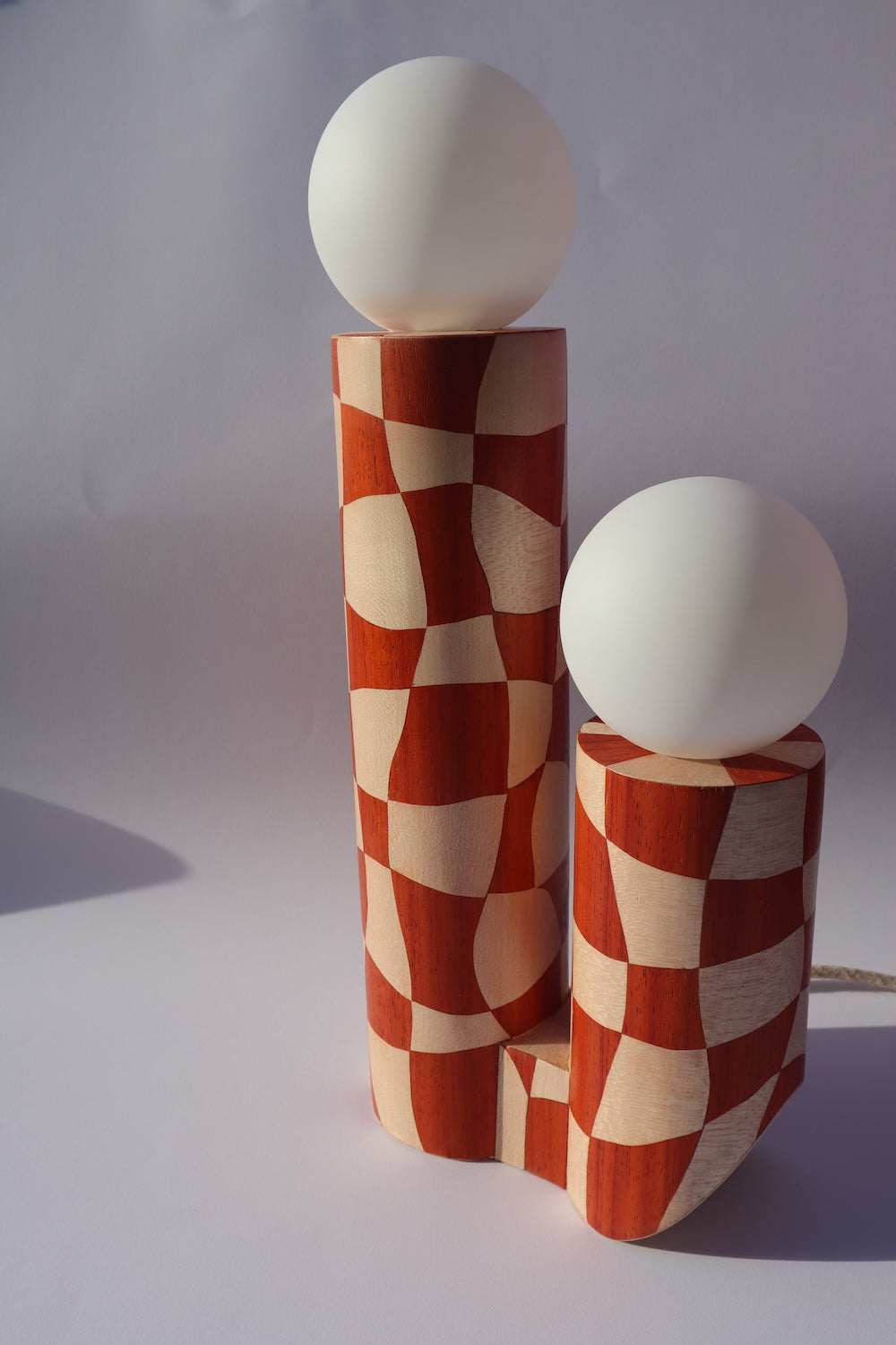 Lampe en marqueterie de bois et sa robe à carreaux pour Ome éditions. Damier en bois de padouk (bois rouge) et Sycomore (bois blanc). Pièce fabriquée à la main par Hermine Torikian, notre artiste ébéniste. Son atelier est à Paris. Lampe à poser sur une étagère, un table de chevet, dans une bibliothèque...
