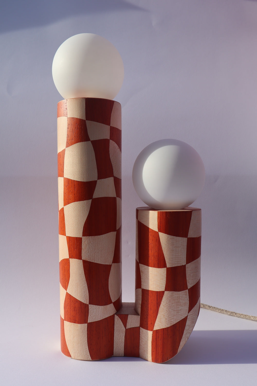 Lampe en marqueterie de bois et sa robe à carreaux pour Ome éditions. Damier en bois de padouk (bois rouge) et Sycomore (bois blanc). Pièce fabriquée à la main par Hermine Torikian, notre artiste ébéniste. Son atelier est à Paris. Lampe à poser sur une étagère, un table de chevet, dans une bibliothèque...