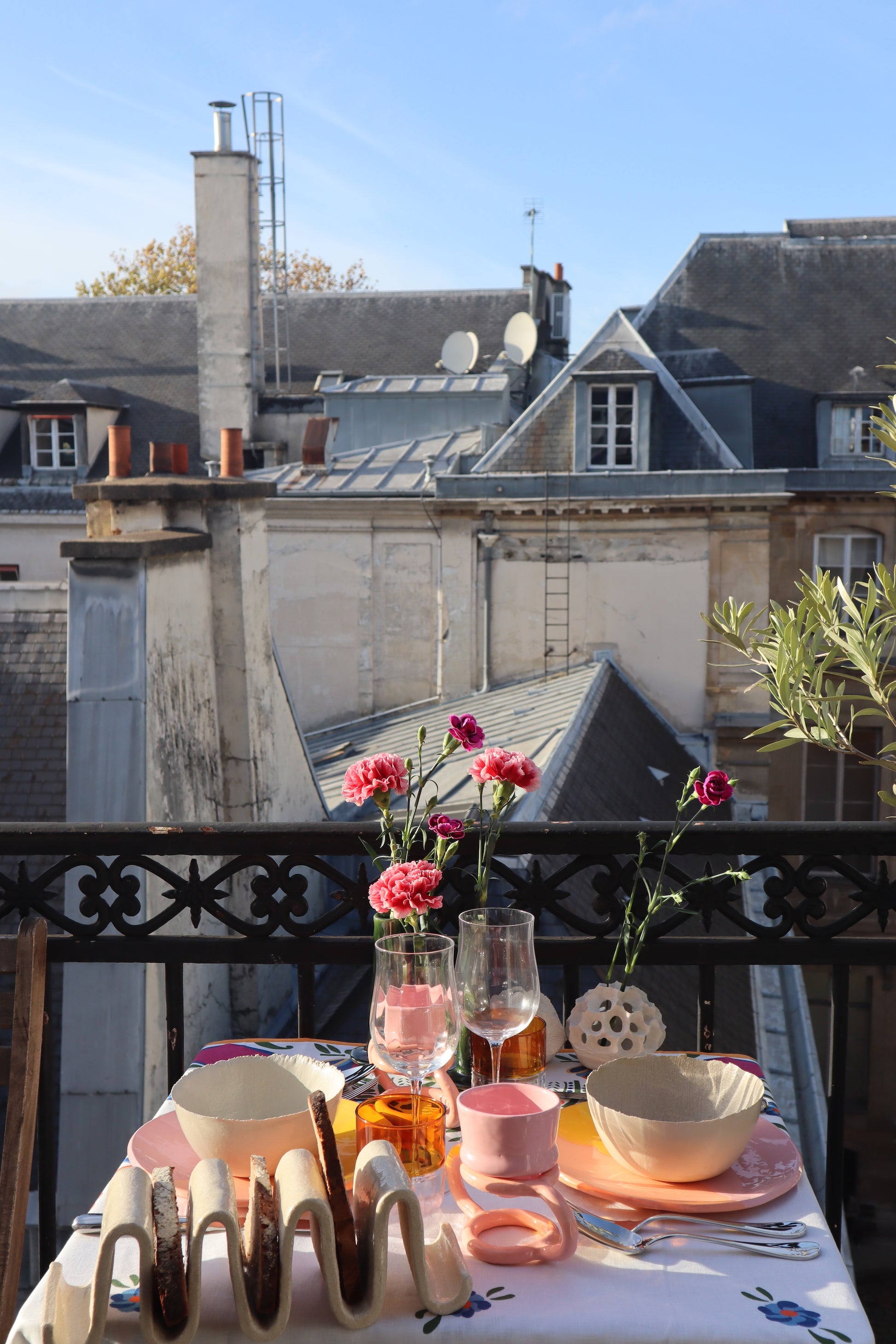 Table colorée sur balcon parisien. Vue sur les toits de Paris. Art de la table par des artisans français, fait à la main.